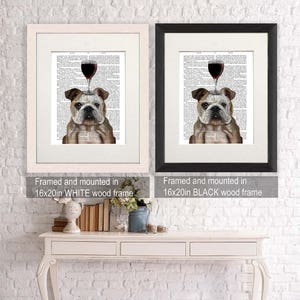 May include: Two framed prints of a bulldog with a glass of red wine on its head. The prints are framed in white and black wood frames. The frames are 16 inches by 20 inches.