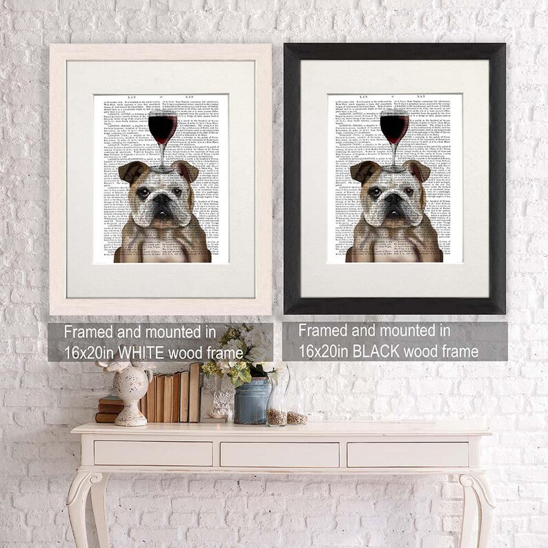 May include: Two framed prints of a bulldog with a glass of red wine on its head. The prints are framed in white and black wood frames. The frames are 16 inches by 20 inches.