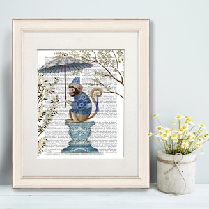 May include: Framed art print featuring a monkey in a blue patterned sweater and hat, holding a matching umbrella. The monkey sits atop a blue and white decorative vase. The background is a vintage book page with floral accents.