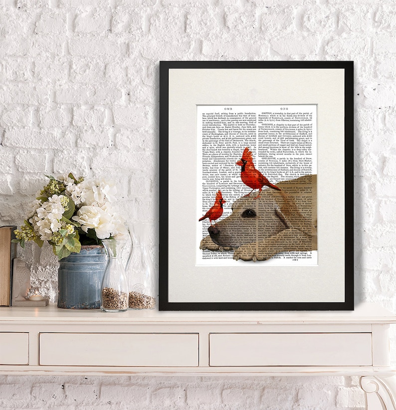May include: A framed print of a dog's head with three red cardinal birds perched on top of it. The image is printed on a vintage book page with text.