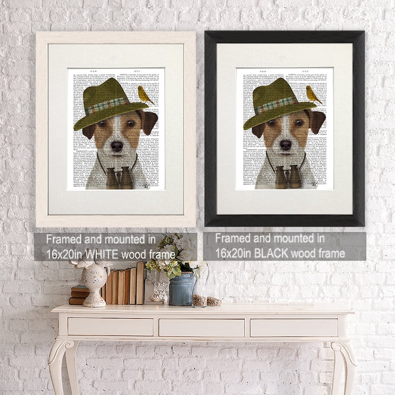 May include: A framed print of a Jack Russell Terrier wearing a green hat and holding binoculars. The dog is surrounded by a black and white text background. The print is available in a white or black frame.
