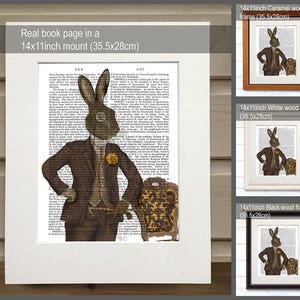 May include: A brown rabbit wearing a suit and glasses sits in a chair. The rabbit is holding a book. The image is printed on a book page and framed in a brown wood frame. The frame is 14 inches by 11 inches and measures 35.5 centimeters by 28 centimeters.