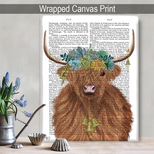 May include: A Highland cow with a floral crown made of blue and green flowers on a vintage book page background. The cow is brown and white with a long, shaggy coat. The book page text is in black and white.