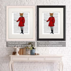May include: Two framed prints of a fox wearing a red hunting jacket and holding a riding crop. The prints are framed in white and black wood frames. The text below the prints reads "Framed and mounted in 16x20in WHITE wood frame" and "Framed and mounted in 16x20in BLACK wood frame".