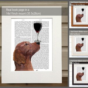 K&ouml;nnte beinhalten: Ein brauner Hund mit einem Glas Rotwein im Maul. Der Hund ist auf einer Buchseite mit Text gedruckt. Das Bild ist in einem 14x11 Zoll gro&szlig;en Karamellholzrahmen gerahmt.