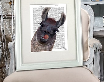 May include: A framed print featuring a llama with its tongue sticking out. The llama image is superimposed on a vintage dictionary page. The frame is white, and the print is displayed on a decorative chair.