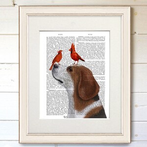 Puede incluir: Impresi&oacute;n art&iacute;stica enmarcada que presenta un beagle con dos cardenales rojos posados en su cabeza. El beagle se encuentra sobre un fondo de p&aacute;gina de diccionario antiguo. El marco blanco rodea la obra, una encantadora representaci&oacute;n de la naturaleza.