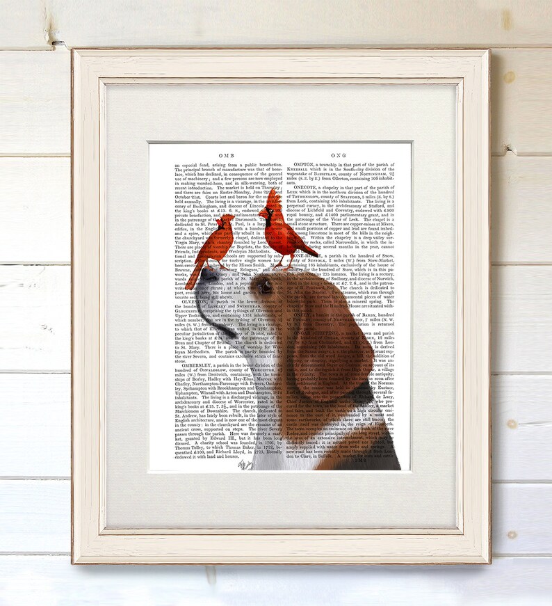 Puede incluir: Impresi&oacute;n art&iacute;stica enmarcada que presenta un beagle con dos cardenales rojos posados en su cabeza. El beagle se encuentra sobre un fondo de p&aacute;gina de diccionario antiguo. El marco blanco rodea la obra, una encantadora representaci&oacute;n de la naturaleza.