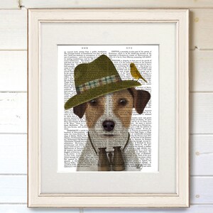 May include: A brown and white Jack Russell Terrier wearing a green and brown hat with a plaid band, binoculars, and a yellow bird perched on the hat. The dog is looking at the camera. The background is a vintage book page.