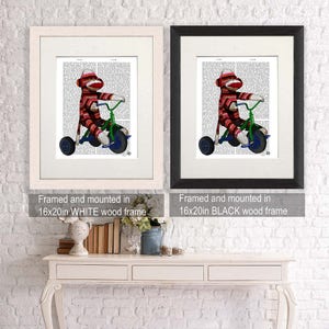 May include: Two framed prints of a sock monkey riding a tricycle on a vintage book page background. The frames are 16x20 inches and are shown in white and black.