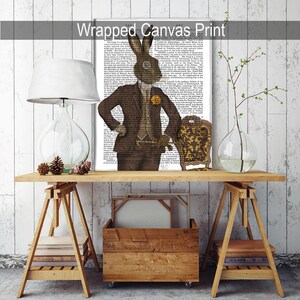 May include: A wrapped canvas print featuring a brown rabbit wearing a suit and a monocle, standing next to a gold chair. The background is a vintage book page.