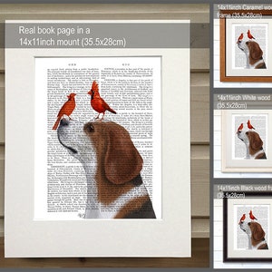 Puede incluir: Impresi&oacute;n enmarcada de un beagle con dos cardenales rojos, sobre un fondo de p&aacute;gina de libro antiguo. La obra de arte est&aacute; disponible en un montaje de 35,5x28 cm, con opciones de marco de madera en color caramelo, blanco y negro. El texto dice: 'Real book page in a 14x11inch mount (35.5x28cm)'