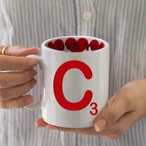 Op de afbeelding: Een witte keramische mok met een rood "C3" ontwerp. De mok heeft een rood hartpatroon aan de binnenkant.