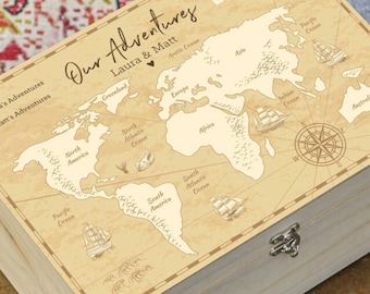 May include: A wooden box with a map of the world on the lid. The map is in a vintage style and includes the names of continents and oceans. The box has a silver latch and is labelled "Our Adventures Laura & Matt".