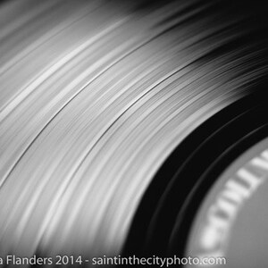 Puede incluir: Primer plano de un disco de vinilo negro con surcos y una etiqueta que dice "Vinyl", mostrando el detalle de la superficie del disco.