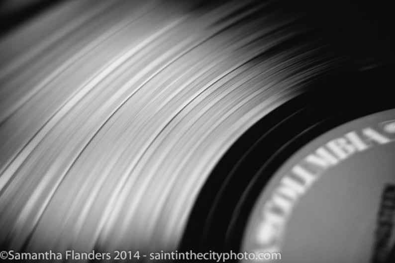 Puede incluir: Primer plano de un disco de vinilo negro con surcos y una etiqueta que dice "Vinyl", mostrando el detalle de la superficie del disco.