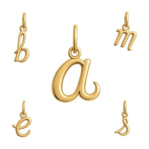 May include: Five gold-colored cursive letter charms, including 'a', 'b', 'e', 'm', and 's'. Each charm has a small loop at the top for hanging. The letters are in a flowing script style, with a polished, reflective surface.