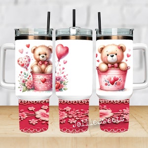 May include: Three stainless steel tumblers with a white background and a pink and white design featuring a teddy bear holding a heart balloon and sitting in a pink bucket. The tumblers have a pink and white floral design on the bottom.