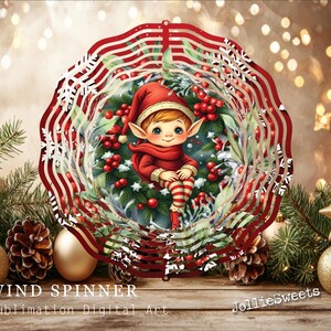 Puede incluir: Un móvil eólico navideño con un elfo de dibujos animados vestido de rojo, rodeado de una corona de bayas y vegetación. El móvil tiene un diseño a rayas rojas y blancas. Las palabras "Wind Spinner" y "Sublimation Digital Art" están en la parte inferior.