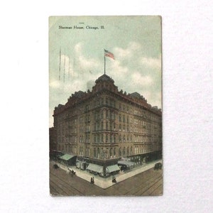 May include: Vintage postcard featuring the Sherman House in Chicago, Illinois. The building is a large, multi-story structure with a prominent corner entrance. An American flag flies atop the building. The postcard has a faded, aged appearance.