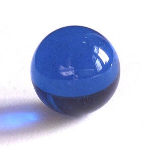 May include: A blue glass marble with a light blue top and a darker blue bottom.
