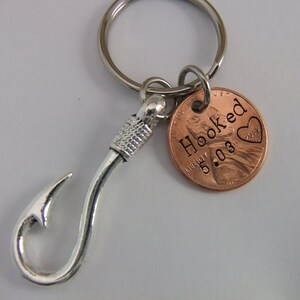 May include: A silver fishing hook keychain with a copper penny charm that says "Hooked 2013" with a heart.