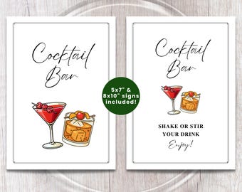 May include: Two white framed signs with the words "Cocktail Bar" in elegant script. One sign features a red cocktail and an old fashioned. The other sign says "Shake or Stir Your Drink, Enjoy!" with illustrations of cocktails.