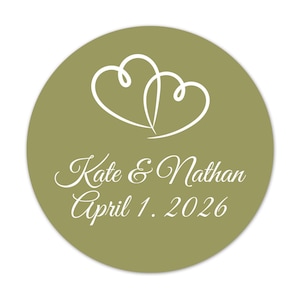 May include: A round, olive-green sticker with white text and a white intertwined heart design. The text reads "Kate & Nathan" and "April 1, 2026". The sticker is likely for a wedding or engagement.