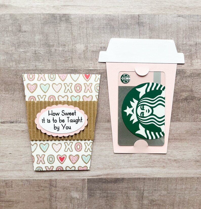 May include: A pink and white coffee cup gift card holder with a brown cardboard sleeve. The sleeve has a white oval with the text "How Sweet It is to be Taught by You".