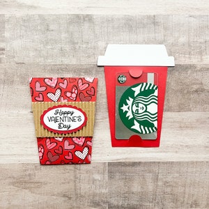 May include: A red and brown paper coffee cup with a heart pattern and the text "Happy Valentine's Day". A Starbucks gift card is inside the cup.