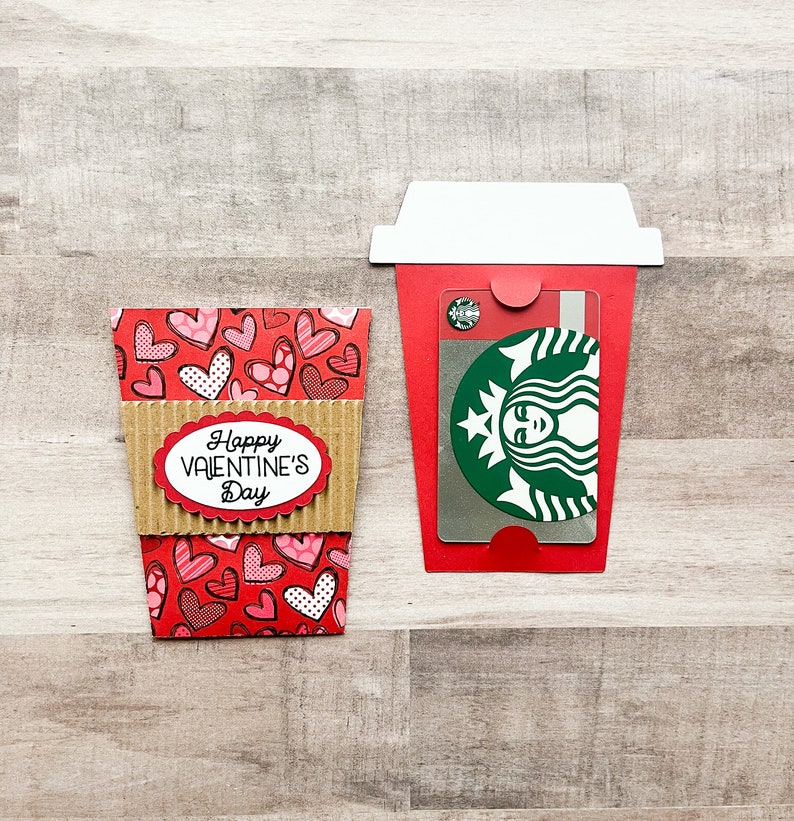 May include: A red and brown paper coffee cup with a heart pattern and the text "Happy Valentine's Day". A Starbucks gift card is inside the cup.
