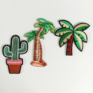 May include: Three embroidered patches featuring tropical designs. A green cactus in a brown pot, a palm tree with a brown trunk and green leaves, and a palm tree with green and beige leaves and a red trunk. Each patch has a black border.