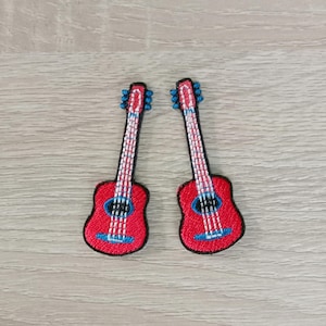 以下が含まれることがあります： 白と青のディテールが付いた赤い刺繍のギターパッチが2つ。パッチは、衣服、バッグ、その他のクラフトに音楽的なタッチを加えるのに最適です。