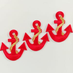 May include: Three embroidered patches, each shaped like a red anchor with a gold rope wrapped around the central shaft. The anchors feature a circular ring at the top and two pointed flukes at the base, all rendered in a dense, textured stitch.