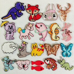 Könnte beinhalten: Eine Sammlung von einundzwanzig bestickten Aufbügel-Patches mit verschiedenen Tieren und Insekten, darunter ein violetter Dinosaurier, ein roter Fuchs, ein rosa Kaninchen, ein Hirsch, ein Bär mit Regenschirm, ein Pferd, ein Delfin, ein Seepferdchen und Schmetterlinge.