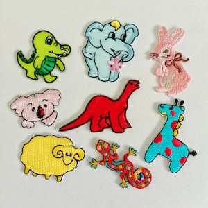 May include: A collection of embroidered animal patches, including a green alligator, a blue elephant, a pink rabbit, a pink koala, a red dinosaur, a yellow sheep, a colorful lizard, and a blue giraffe with red spots.
