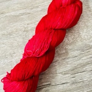 Puede incluir: Un ovillo de hilo rojo brillante, perfecto para tejer o hacer ganchillo.