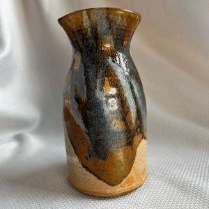 May include: A ceramic vase with a brown, blue, and white glaze. The vase has a rounded body and a narrow neck.