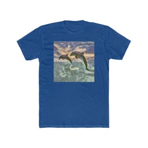 Könnte beinhalten: Ein königsblaues T-Shirt mit einem quadratischen Aufdruck von zwei Delfinen, die aus dem Meer springen. Das Kunstwerk hat einen Aquarell-Effekt und zeigt einen bewölkten Himmel und Wasser. Das T-Shirt ist aus einem weichen, bequemen Material gefertigt.