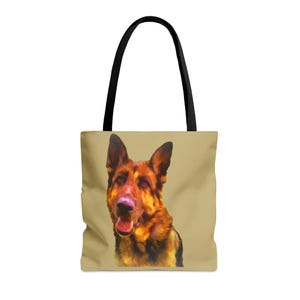 May include: A beige tote bag featuring a watercolor-style portrait of a German Shepherd dog. The dog has brown and black fur with a pink nose and open mouth. The bag has black handles.