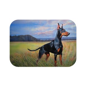 May include: A black and tan Doberman Pinscher stands in a field of tall grass, with a backdrop of a green field, trees, and a cloudy blue sky. The dog is alert, with its ears perked up, and its tail extended.