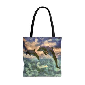 Könnte beinhalten: Tragetasche mit einem Gemälde von zwei Delfinen, die aus dem Meer springen. Das Kunstwerk hat einen strukturierten, malerischen Stil mit Blau-, Grün- und Beigetönen. Die Tasche hat einen schwarzen Griff und einen weißen Hintergrund.