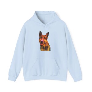 May include: A light blue hoodie featuring a German Shepherd dog graphic on the front. The dog has brown and black fur and is centered on the chest of the hoodie. The hoodie has a kangaroo pocket and a drawstring hood.