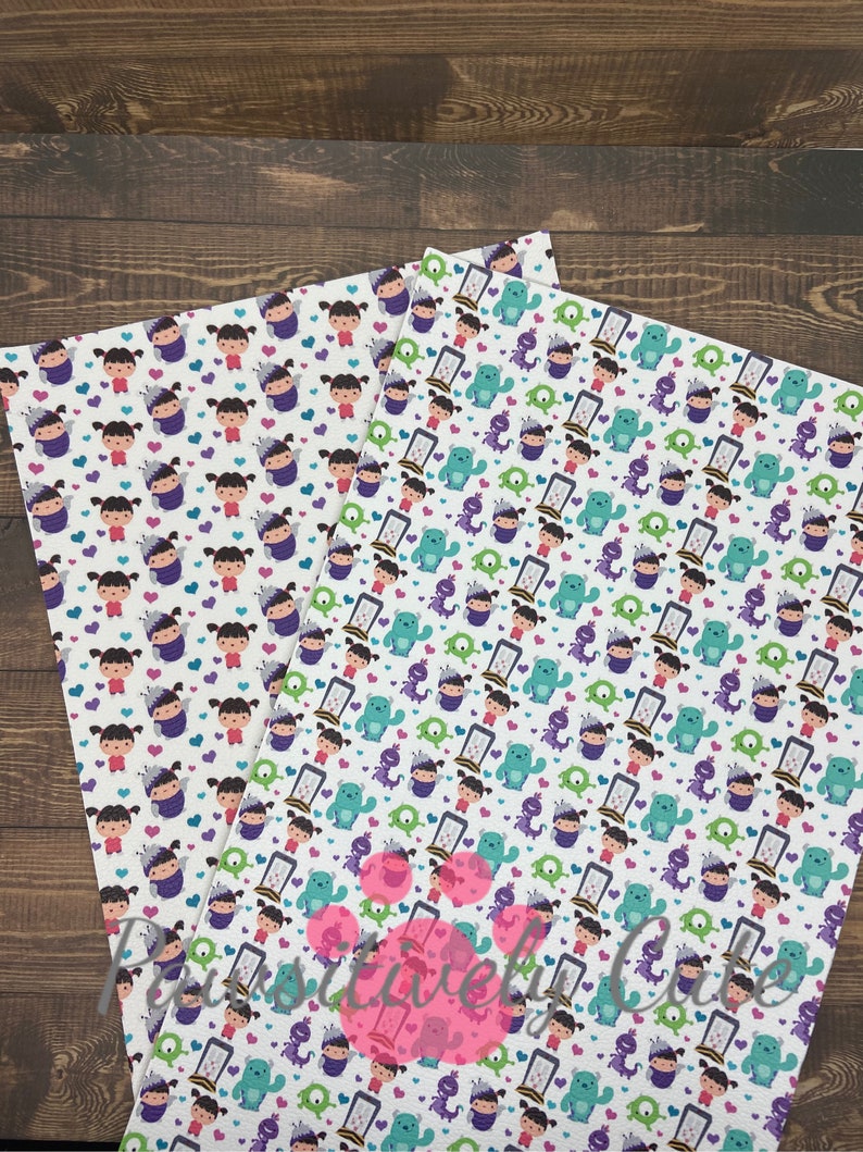 May include: Two sheets of white fabric with a repeating pattern of cartoon characters from the movie Monsters Inc. The characters include Sully, Mike, Boo, and the door. The fabric is printed with purple, green, blue, and pink colors.