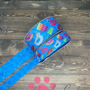 May include: Two rolls of blue and white ribbon with a summer theme. The ribbon features a pattern of watermelons, donuts, flamingos, and pool floats.