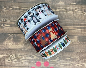 Peut inclure: Trois rouleaux de ruban de Noël à thème canin. Le premier rouleau a un motif à carreaux noir et blanc avec des chiens portant des chapeaux de Père Noël. Le deuxième rouleau a un motif à carreaux rouge et bleu avec des chiens portant des chapeaux de Père Noël. Le troisième rouleau a un fond blanc avec des chiens portant des chapeaux de Père Noël et des sapins de Noël.