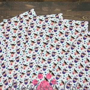 May include: A stack of white fabric sheets with a repeating pattern of a cartoon girl wearing a purple costume and a crown. The girl is surrounded by small purple, pink, and blue hearts.