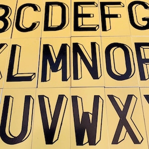 Letras vintage negras y amarillas para letreros, alfabeto metálico para boletines, letras pequeñas para decoración industrial y técnicas mixtas.