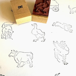 May include: A set of rubber stamps featuring various animal illustrations, including a cat, a duck, a cow, and a dog. The stamps are mounted on wooden blocks and are ready to be used for crafting and scrapbooking.