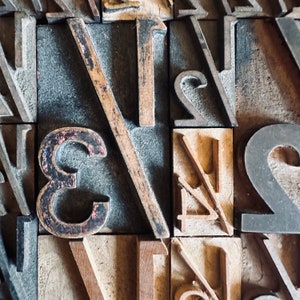 May include: Close-up of wooden printing blocks with the numbers 1, 2, 3, and 4, and the fraction 1/2. The blocks are arranged in a grid pattern and have a worn, vintage look.